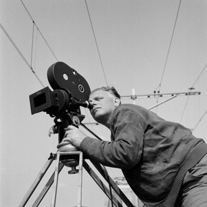 849531 Afbeelding van cineast Herman Wassenaar tijdens het filmen van treinen bij de spoorbrug over het ...